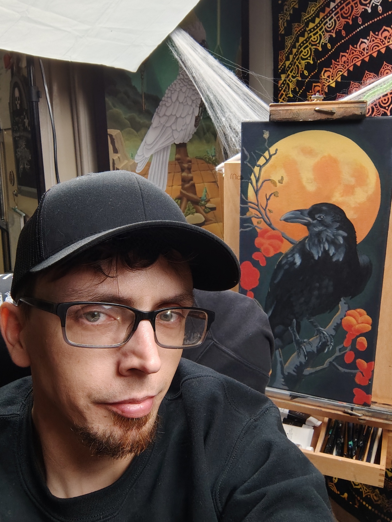 The artist in the studio working on a raven and harvest moon painting